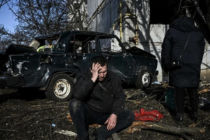 Ein verzweifelter Mann sitzt in der ostukrainischen Stadt Tschuhujiw vor einem Gebäude, das beim Beschuss durch russische Streitkräfte zerstört wurde (24. Februar 2022). © ARIS MESSINIS/AFP via Getty Images